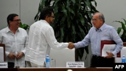 FARC guerrilla commander Ivan Marquez, center, and the head of the Colombian delegation for peace talks, Humberto de la Calle, shake hands after signing a new peace agreement next to Cuban Foreign Affairs Minister Bruno Rodriguez Parrilla in Havana, Nov. 12, 2016.