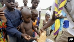 A man distributes bread to children at St. Ambrose church in Angree, Abidjan, a temporary refuge for people fleeing from clashes between forces loyal to incumbent president Gbagbo and his rival Ouattara (File Photo - March 1, 2011)