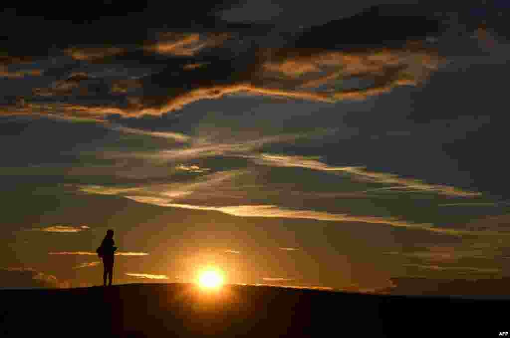 A woman watches the sunset in the Olympic park in Munich, southern Germany, after a cold day on March 18, 2019. 