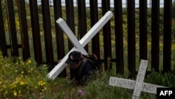 Un migrante lleva una cruz mientras camina a lo largo de la frontera entre México y Estados Unidos, mientras participa en el Camino de la Cruz de los Migrantes en Playas de Tijuana, Estado de Baja California, México, el 10 de abril de 2020.