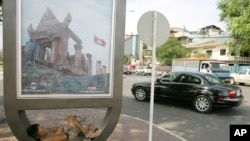 FILE - A Cambodian homeless man, left, sleeps under a Cambodia's Preah Vihear temple sign board in Phnom Penh, Cambodia.