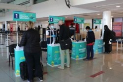 FILE - Passengers are checked in a sanitary control stations in the international passenger arrival area at Santiago International Airport, as Chile recorded on Dec. 29, 2020, its first case of the British COVID variant, in Santiago, Dec. 21, 2020.