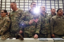 FILE - A United States Airman holds up an American Flag as U.S. President Donald Trump delivers remarks to military personnel in an unannounced visit to Bagram Air Base, Afghanistan, Nov. 28, 2019.