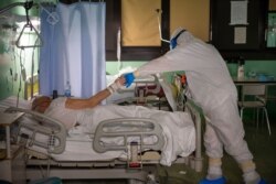 Dr. Giovanni Passeri, right, is shown gratitude by an 81-year-old patient who is being administered oxygen in the COVID-19 section of the Maggiore Hospital in Parma, northern Italy, April 8, 2020.