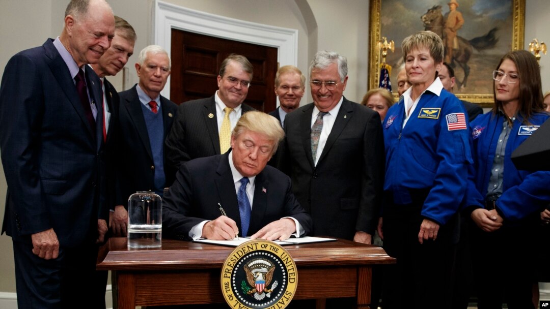 President Donald Trump signs a policy directive to send American astronauts back to the moon, and eventually Mars, in the Roosevelt Room of the White House, Dec. 11, 2017, in Washington.