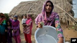 A village woman displays a vessel damaged by gunfire allegedly from the Pakistan side of the border at Jora Farm village in the India-Pakistan border Ranbir Singh Pura region, about 35 kilometers (22 miles) from Jammu, India, Aug. 23, 2014.