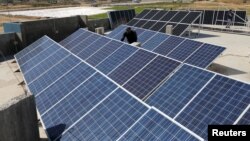 A Palestinian worker installs solar panels atop the roof of a medical center in Gaza City, March 1, 2016.