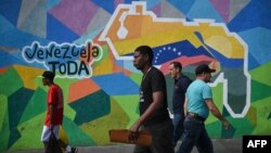 Personas caminan frente a un mural en la comunidad del 23 de Enero, en Caracas, a favor del referendo consultivo sobre el Esequibo. La votación se realizará este domingo en toda Venezuela.