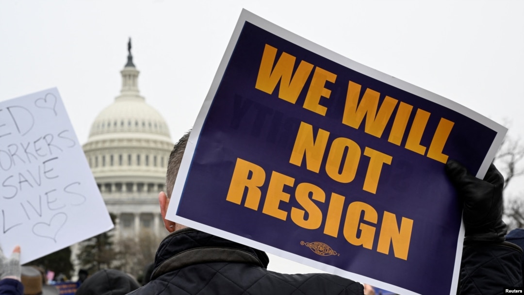 A person displays a sign as labor union activists rally in support of federal workers during a protest, with the U.S. Capitol in the background on Capitol Hill in Washington, Feb. 11, 2025. 