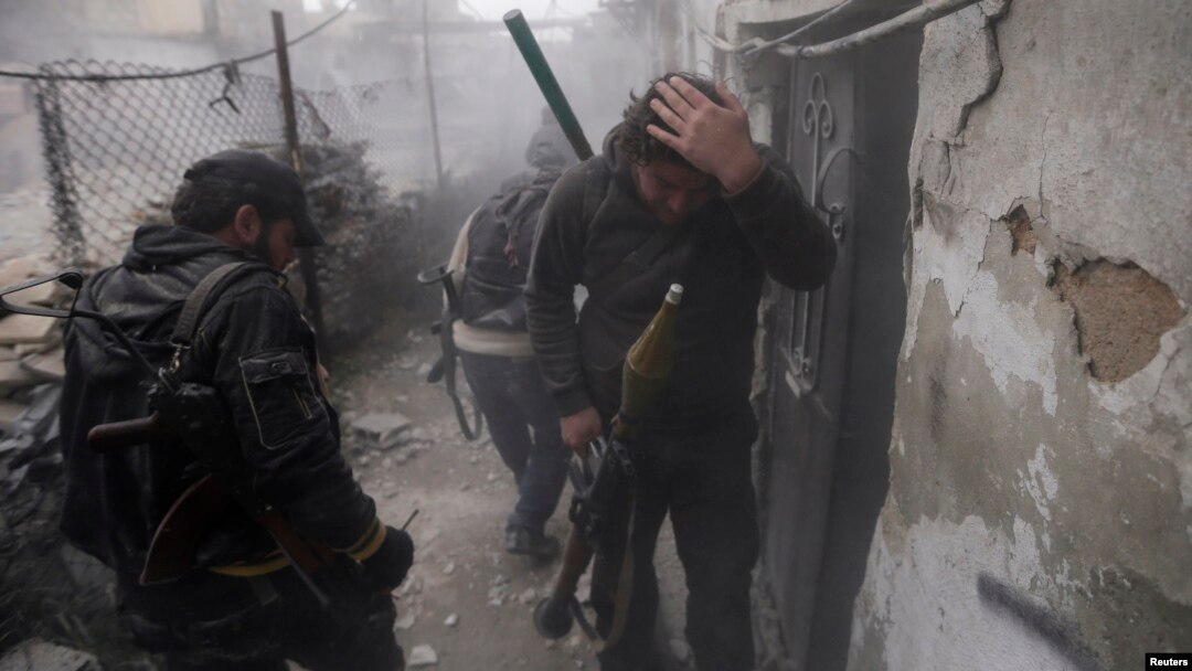 A Syrian rebel grabs his head as the smoke subsides, during fighting between the two sides in the Ain Tarma neighborhood of Damascus. Jan. 13, 2013