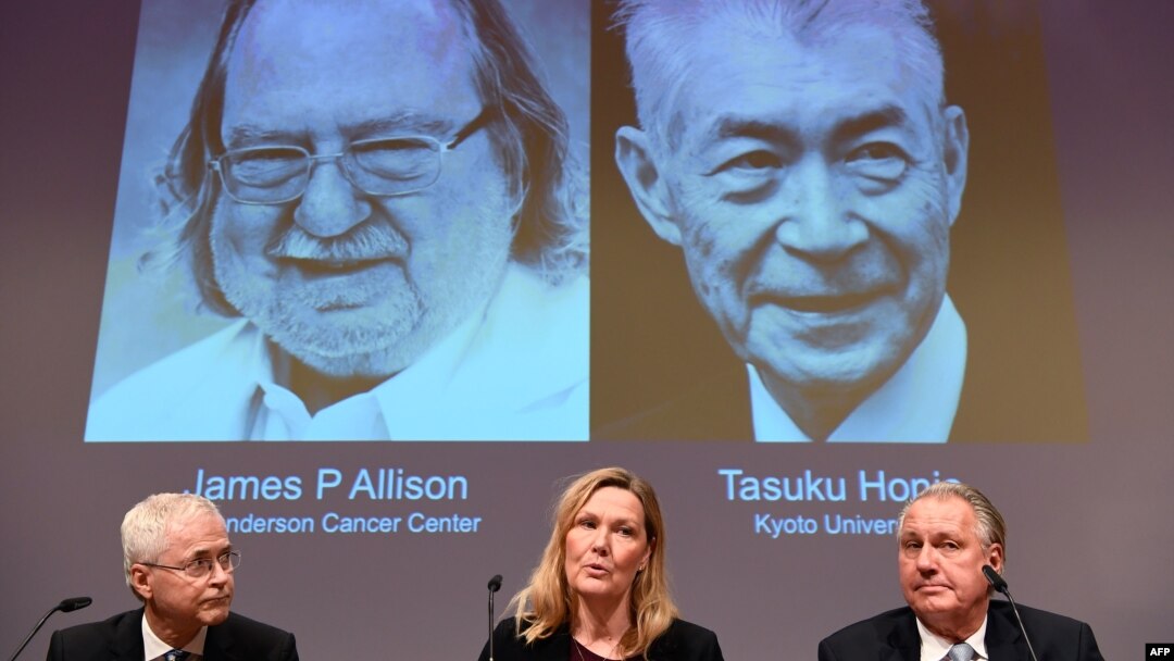 Anggota Komite Nobel untuk bidang Fisiologi atau Kedokteran (kiri ke kanan) Edvard Smith, Anna Wedell, dan Klas Kaerre duduk di depan layar yang menampilkan potret James Allison (kiri) dan Tasuku Honjo dalam pengumuman pemenang Hadiah Nobel 2018 dalam bidang Fisiolog (ilmu faal) atau Kedokteran, di Institut Karolinska, Stockholm, Swedia, 1 Oktober 2018.