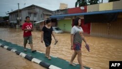 Warga berjalan di pemisah jalan untuk menghindari banjir di Kota Bahru, 28 Desember 2014. 