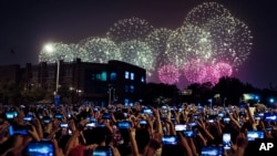 FILE - People use smartphones to film fireworks exploding at Tiananmen Square in Beijing on Oct. 1, 2019, as part of a gala evening commemorating the 70th anniversary of the founding of Communist China.