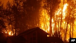 Un incendio forestal arde detrás de una casa en Twisp, estado de Washington, el miércoles, 19 de agosto de 2015.