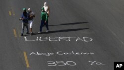 Manifestantes antigubernamentales caminan ante un mensaje en el que invocan el artículo 350 de la Constitución que da derecho a rebelarse contra la injusticia.