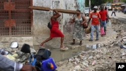 Los peatones cruzan un charco de agua en el centro de Puerto Príncipe, Haití, el lunes 23 de septiembre de 2024.