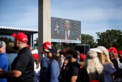 Supports watch a screen and wait in line before President Donald Trump's rally on Nov. 26, 2019, in Sunrise, Fla.