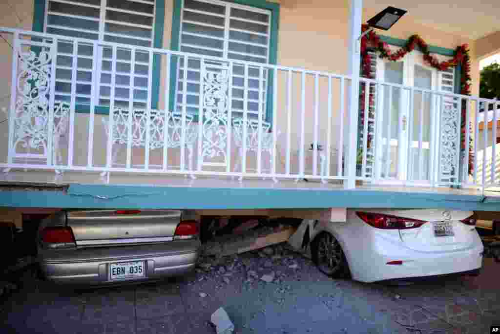 Cars are crushed under a home that collapsed after an 5.8-magnitude earthquake hit Guanica, Puerto Rico. 