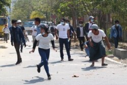 Manifestantes huyen en Mandalay, Myanmar, cuando la policía lanza gas lacrimógeno a una protesta contra el golpe militar en el país. Febrero 28 de 2021.