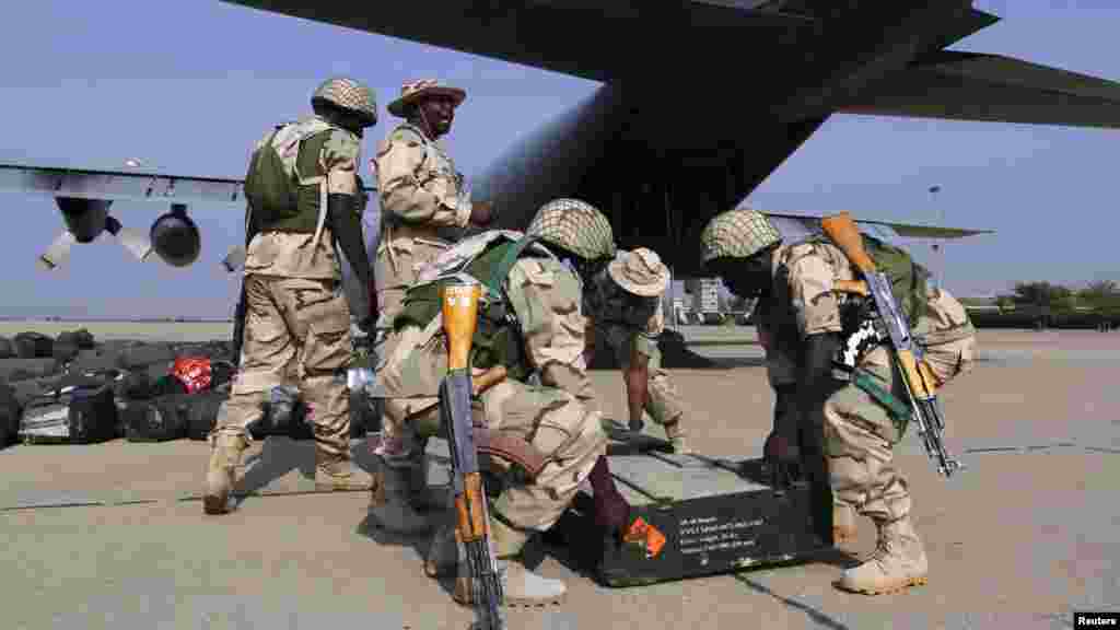 Nigerian soldiers prepare to load weapons stored in boxes into a military plane before leaving for Mali.