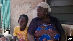 FILE - Funmilayo Kotun, a 66-year-old malaria patient, sits with her grandson Ayomide Kotun outside her house in the Makoko neighborhood of Lagos, Nigeria, on April 20, 2024.