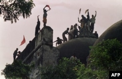 FILE - Hindu fundamentalists shout and wave banners as they stand atop a stone wall as they celebrate the destruction of the 16th Century Babri Mosque at a disputed holy site in the city of Ayodhya on December 6, 1992. (Photo by Douglas E. CURRAN / AFP)