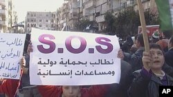 Protesters hold a banner reading, "Demand international protection and humanitarian aid" during a protest against Syria's President Bashar al-Assad in Al Qusour, Homs, March 2, 2012.