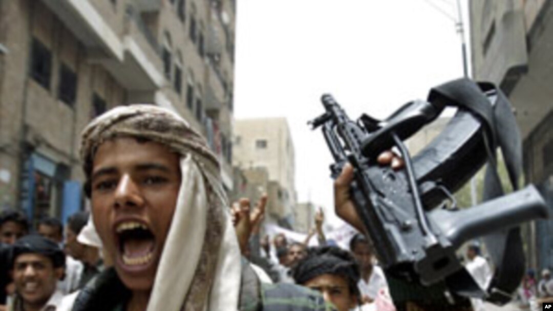 An opposition follower escorting anti-government protesters shouts slogans as he holds up his rifle during a demonstration to demand the ouster of Yemen's President Ali Abdullah Saleh in the southern city of Taiz, July 21, 2011