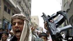 An opposition follower escorting anti-government protesters shouts slogans as he holds up his rifle during a demonstration to demand the ouster of Yemen's President Ali Abdullah Saleh in the southern city of Taiz, July 21, 2011