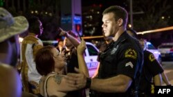 Un policier tente de calmer la foule après l’arrestation d’un suspect en relation avec la fusillade au cours de laquelle au moins cinq agents de la police ont été abattus par des tireurs embusqués lors d’une manifestation antiraciste, à Dallas, 7 juillet 2016. / AFP PHOTO / Laura Buckman