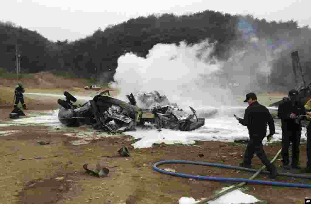 A firefighter tries to extinguish a U.S. Marine helicopter after it made a "hard landing" during an exercise, north of Seoul, April 16, 2013. 