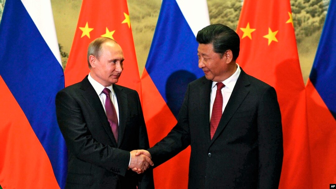 Presiden Rusia Vladimir Putin (kiri) dan Presiden China Xi Jinping berjabat tangan dalam pertemuan di Beijing, Juni 2016.