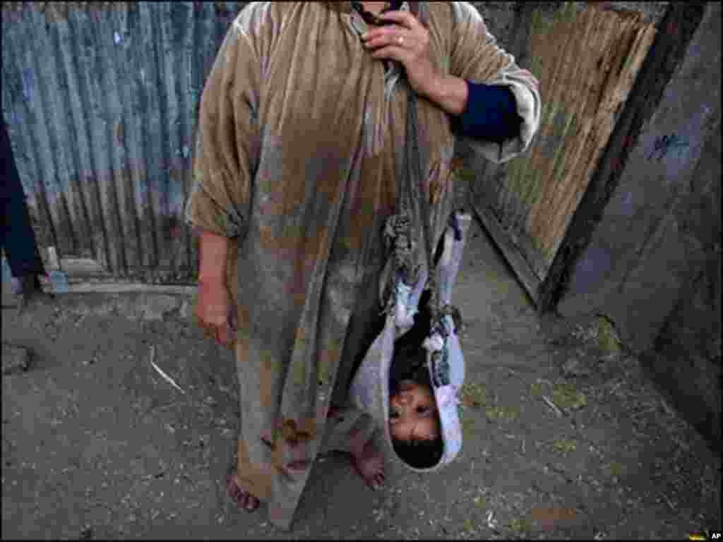 ایک فلسطینی پناہ گزین نے اپنے بچے کو گلے میں اس طرح کپڑا ڈال کر لٹکایا ہوا ہے جیسے گود میں لیا ہو