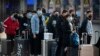 Travelers wear face masks as they stand outside the Beijing Railway Station in Beijing, Jan. 31, 2020. 