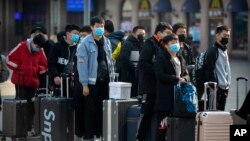 Travelers wear face masks as they stand outside the Beijing Railway Station in Beijing, Jan. 31, 2020. 