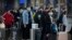 Travelers wear face masks as they stand outside the Beijing Railway Station in Beijing, Jan. 31, 2020. 