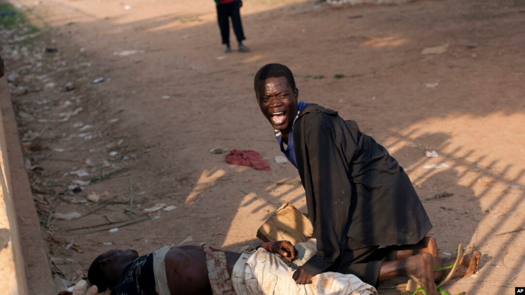 Foto yang diambil pada 23 Desember 2013 menggambarkan seorang pria di samping temannya yang terluka parah dalam kekerasan di Sudan Selatan.