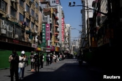 Warga berdiri di jalan menunggu tes asam nukleat saat lockdown di tengah pandemi COVID-19, di Shanghai, China, 17 April 2022. (REUTERS/Aly Song)