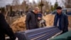 Vova, 10, looks at the coffin carrying body of his mother, Maryna, as his father, Ivan Drahun, hugs him during her funeral in Bucha, on the outskirts of Kyiv, April 20, 2022.