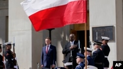 Defense Secretary Lloyd Austin, right, stands with Polish Defense Minister Mariusz Błaszczak, left, as the National Anthem is played during an arrival ceremony at the Pentagon in Washington, Apr. 20, 2022. 