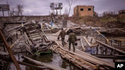 Ukrainian soldiers walk on a destroyed bridge in Irpin, on the outskirts of Kyiv, April 20, 2022.