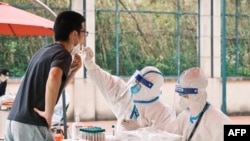 A health worker wearing personal protective equipment conducts a swab test for the Covid-19 coronavirus in a compound during a Covid-19 lockdown in Pudong district in Shanghai on April 19, 2022.