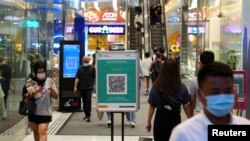 Orang-orang berjalan melewati kode QR untuk aplikasi pelacakan kontak COVID-19 "LeaveHomeSafe" di sebuah pusat perbelanjaan, di distrik Tsim Sha Tsui di Hong Kong, Cina, 21 April 2022. (Foto: REUTERS/Lam Yik)