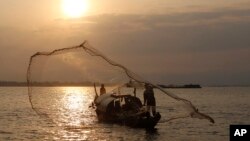 FILE - A Cambodian fisherman casts his fishing net for catching fish in Tonle Sap river, in Phnom Penh, Cambodia, Friday, March 2, 2018. (AP Photo/Heng Sinith)