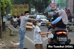 Anggota Jemaah Ahmadiyah Indonesia (JAI) membagikan takjil gratis di depan masjidnya yang disegel. (Foto: Rio Tuasikal/VOA)