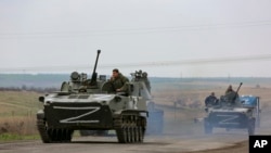 FILE - Russian military vehicles move on a road in an area controlled by Russian-backed separatist forces near Mariupol, Ukraine, April 18, 2022. Some Ethiopians, eager to join Russia's aggression aganst Ukraine, have been lining up at the Russian embassy in Addis Ababa.