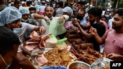 Pedagang kaki lima menyiapkan dan membagikan makanan untuk masyarakat sebelum berbuka puasa pada hari pertama bulan suci Ramadan, di sebuah pasar di Dhaka, Bangladesh, 3 April 2022. (Munir uz zaman / AFP)