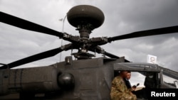 FILE - US soldier presents a military AH-64D Apache helicopter by Boeing at an international military fair in Kielce, Poland, Sept. 7, 2017.