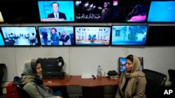 FILE - Afghan journalists Banafsha Binesh, right, speaks with her colleague Wheeda Hassan, at TOLO TV newsroom in Kabul, Afghanistan, Feb. 8, 2022.