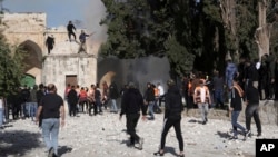 Palestinians work to extinguish a tree that caught fire as Israeli police clashed with protesters at the Al Aqsa Mosque compound, in Jerusalem's Old City, April 22, 2022.
